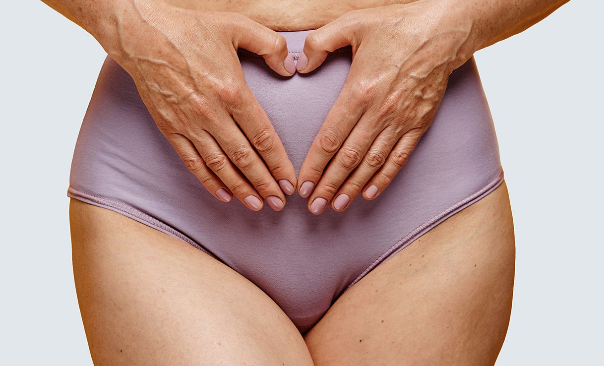 Unterleib einer Frau in lilaner Unterhose, die mit den Händen ein Herz formt