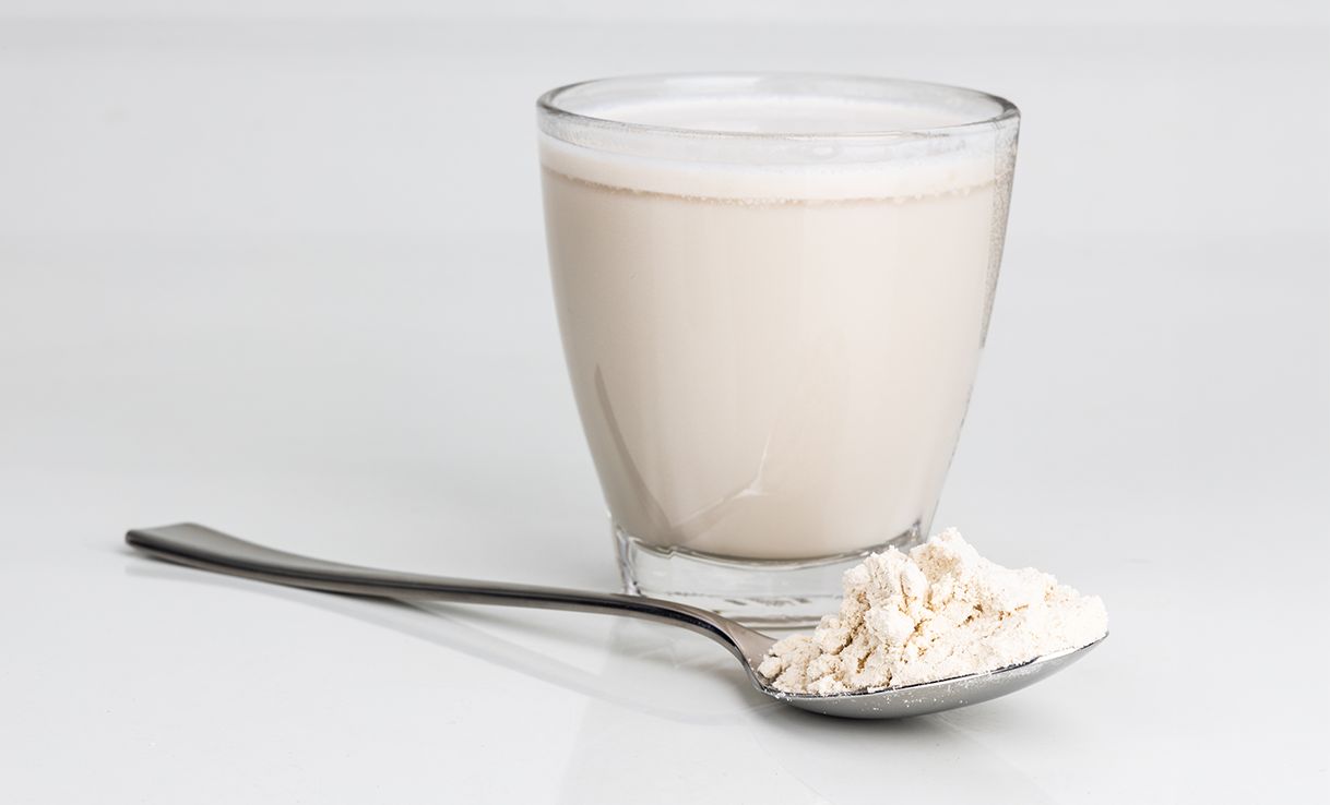 Weißes Getränk im Glas mit einem Löffel daneben