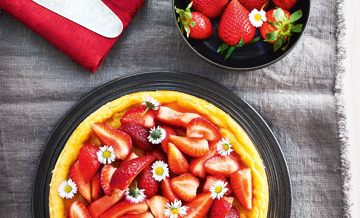 Mandelflan mit Erdbeeren und Gänseblümchen als Topping