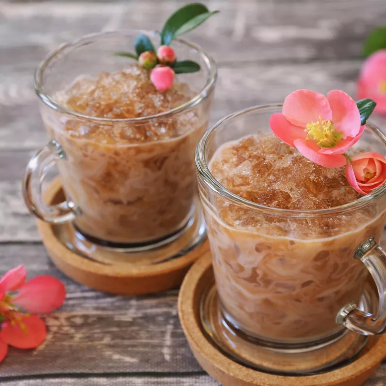Zwei Gläser Granita mit Blumen-Deko auf Untersetzern