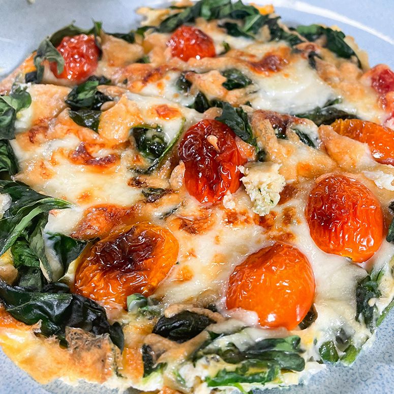 Eierauflauf mit Tomate, Spinat auf hellblauem Teller